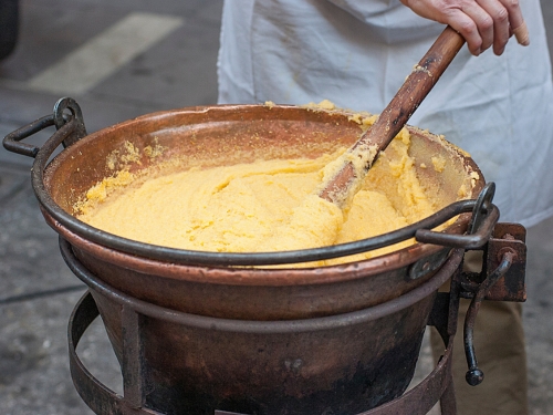 Pentolone con polenta che viene mescolata con mestolo