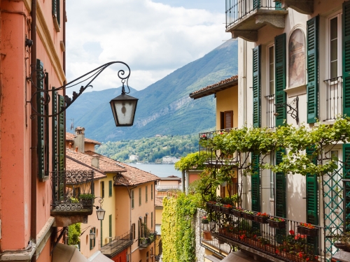 Punto iconico di Bellagio con un palazzo con lampione di fronte ad un altro palazzo e con il lago di Como visibile in lontananza