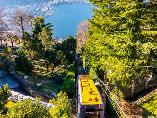 Funicolare esterna con carrozza gialla vista dall'alto e con il lago di como sullo sfondo